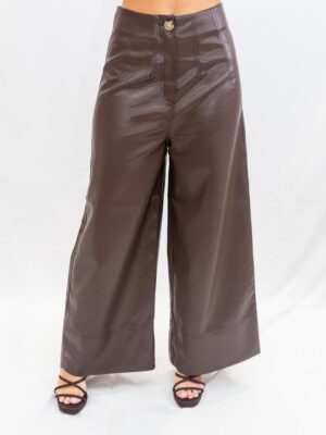 Mujer con pantalón efecto piel color chocolate, corte ancho . Prenda elegante y moderna ideal para looks de temporada.