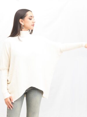 “Mujer con jersey beige de punto D’l Giulia Mastini, cuello cisne y manga ajustada, diseño fluido con pico delantero.”