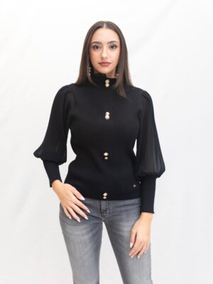 “Mujer con jersey negro de Lemaille con cuello cisne, botones dorados y mangas semi transparentes, prenda elegante de La Acicalá.”